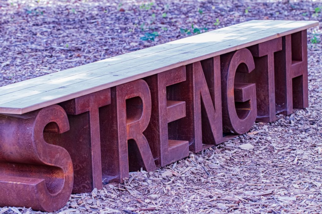 Strength written on a brown wooden fence on gray and white ground